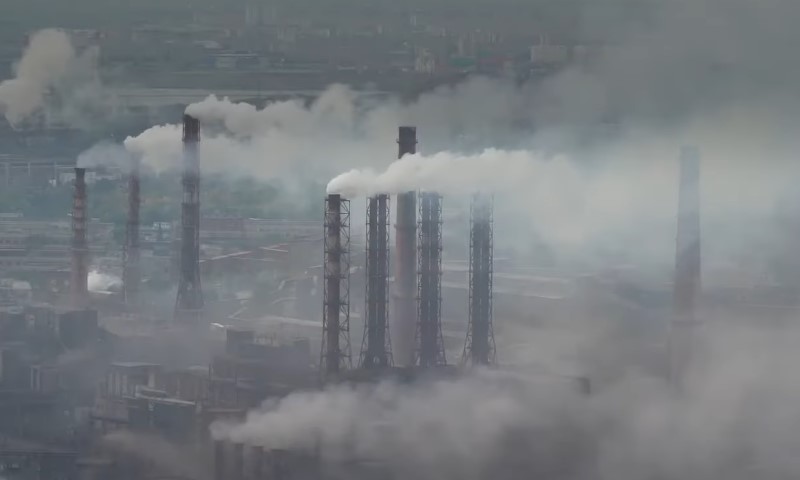 Smoke billows from multiple chimneys at an industrial plant 