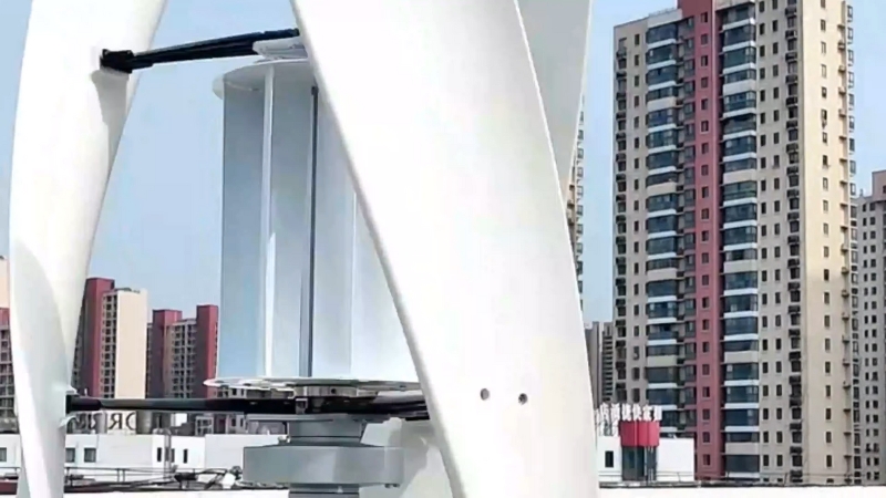 A vertical axis wind turbine sits on a rooftop surrounded by tall apartment buildings