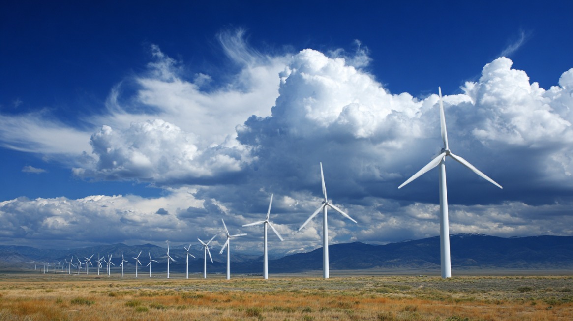 Row of wind turbines stretching across a wide grassland landscape