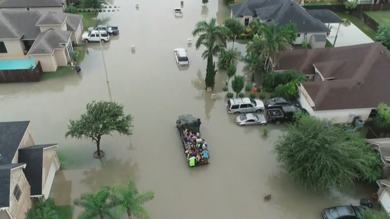 Aerial view of a flooded neighborhood in McAllen, Texas, with a group of people being transported in a boat through the water