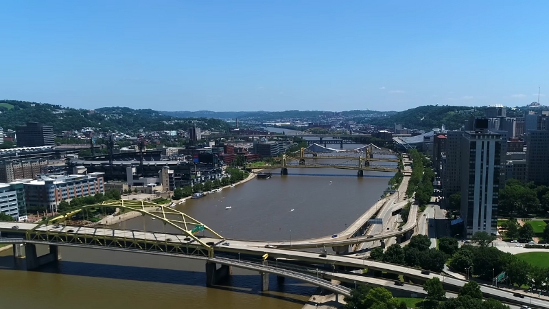 A panoramic view of Pittsburgh with its iconic yellow bridges, rivers, and city skyline