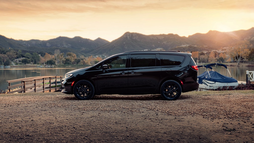 A black Chrysler Pacifica Hybrid parked lakeside at sunset, representing one of the most reliable long-term vehicles for families and road trips