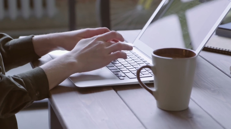 An employee types on a laptop while checking employer benefits for eco-friendly vehicle incentives