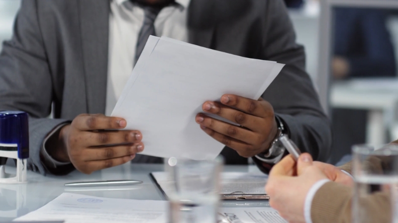 Two people review loan documents during a meeting about financing an eco-friendly vehicle