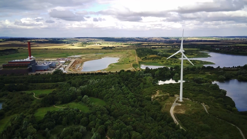A wind turbine stands near a lake and research facility, showing Horizon Europe’s support for climate and energy innovation