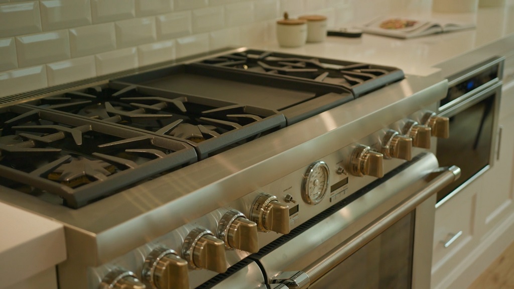 Modern stainless steel stove with multiple gas burners and oven in a contemporary kitchen, highlighting appliance efficiency