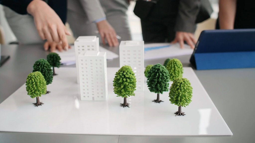 Architectural model with trees and buildings on a table during a meeting about renewable energy and sustainable urban planning