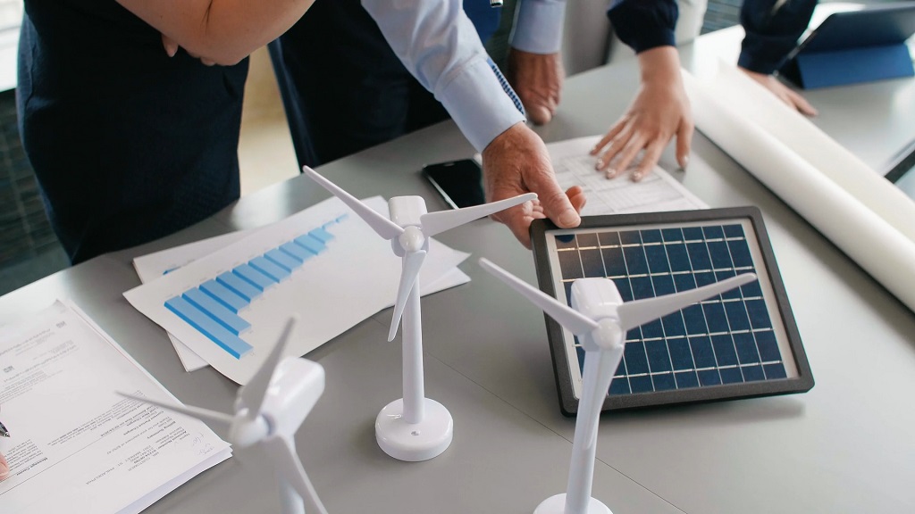 Business team discussing solutions with wind turbine and solar panel models on the table