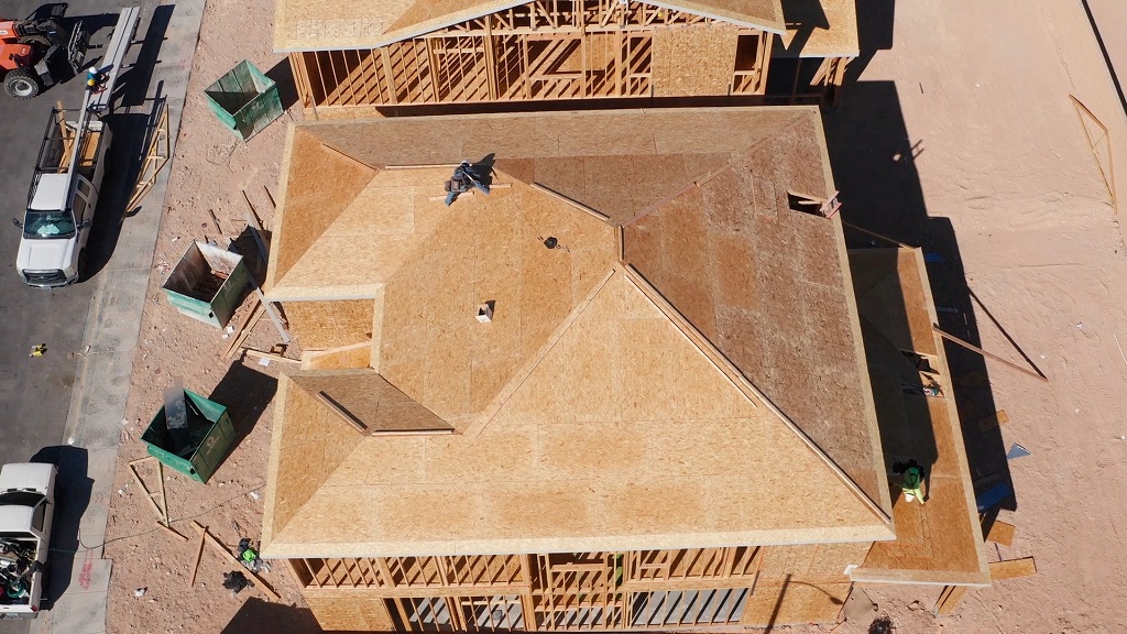 Construction workers measure roof structure during framing to ensure it can hold solar panel weight