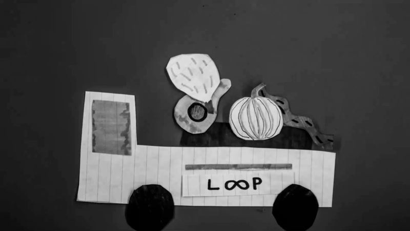 Handmade paper cutout of a truck labeled Loop carrying vegetables, showing circular economy food waste reuse