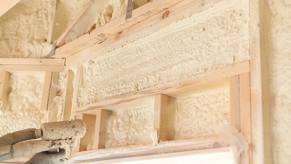 Close-up of spray foam insulation being applied inside wooden wall framing for energy efficiency