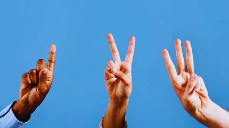 Three hands each show one, two, and three fingers against a plain blue background to represent Scope 1, 2, and 3 emissions