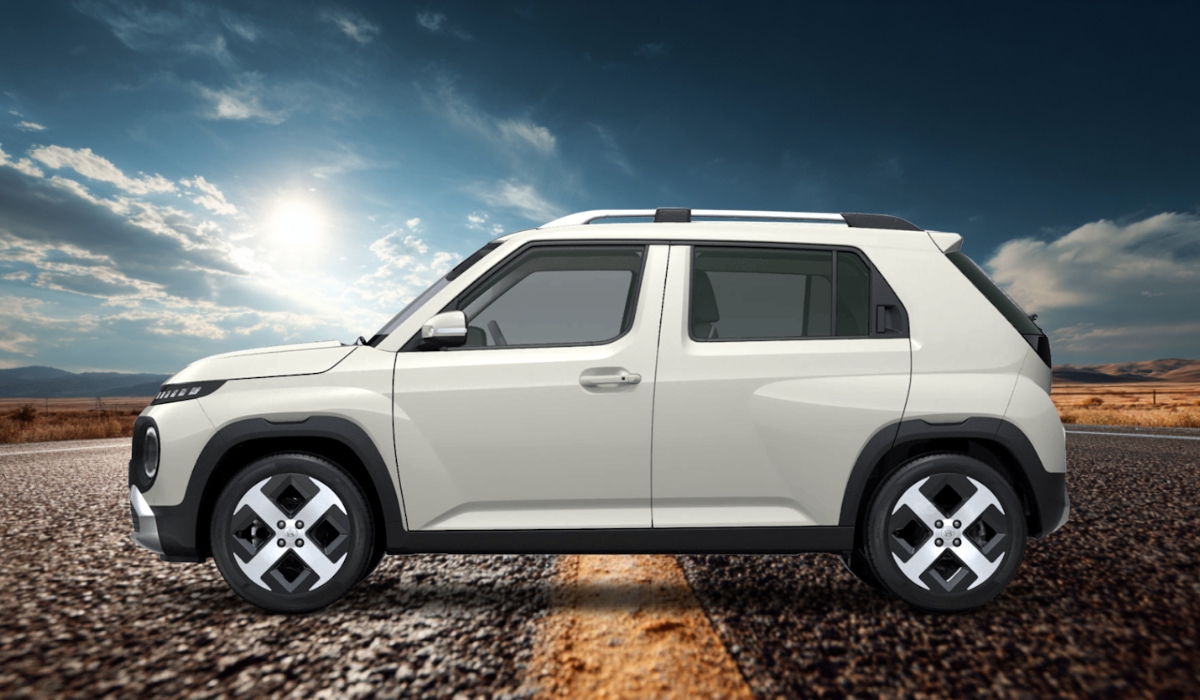 A white Hyundai Inster electric micro-SUV with a boxy design parked on an open road with a bright sky and scenic landscape