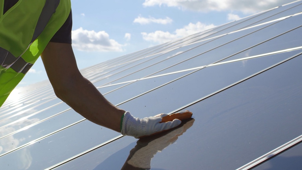 Worker cleaning solar panels during maintenance check