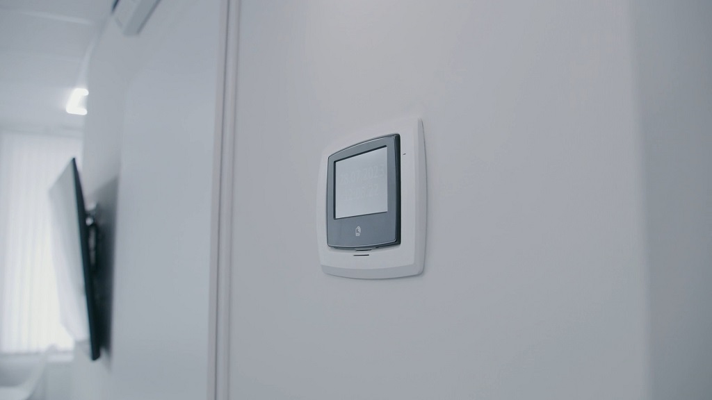 Wall-mounted smart thermostat in a bright room, helping control energy use and reduce household costs