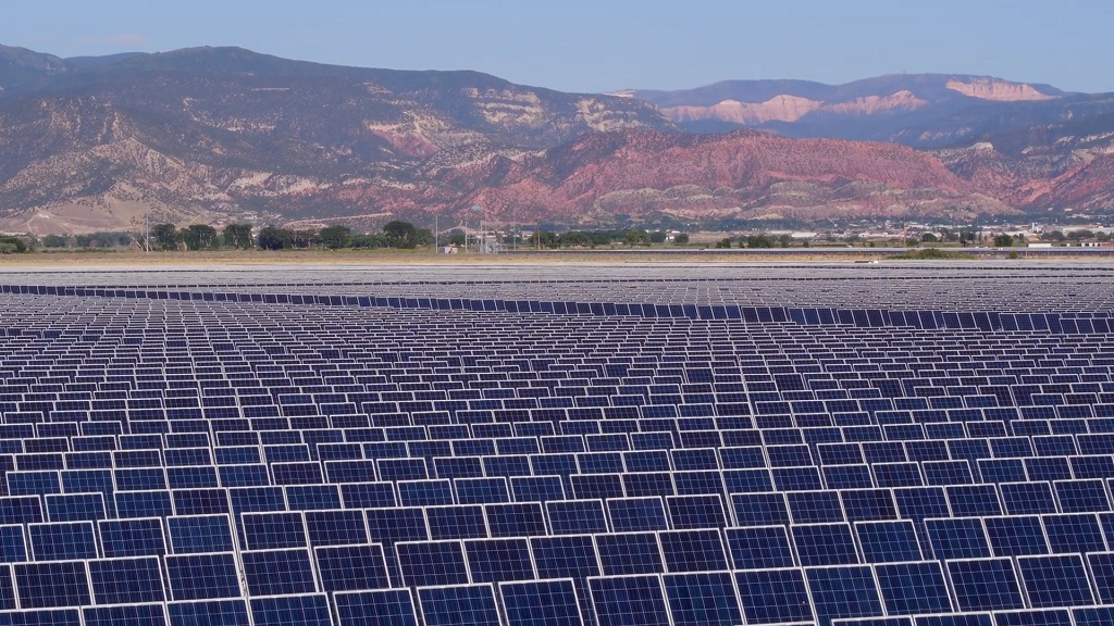 Wide solar array field set against a mountainous backdrop