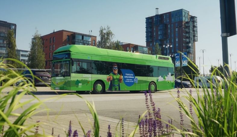 A vibrant green electric bus navigates a city street