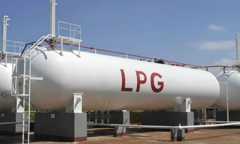 Large white horizontal LPG storage tank with red lettering under a bright blue sky