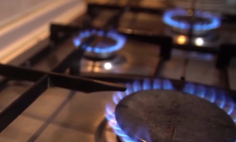 A gas stove with vibrant blue flames burning on the burners