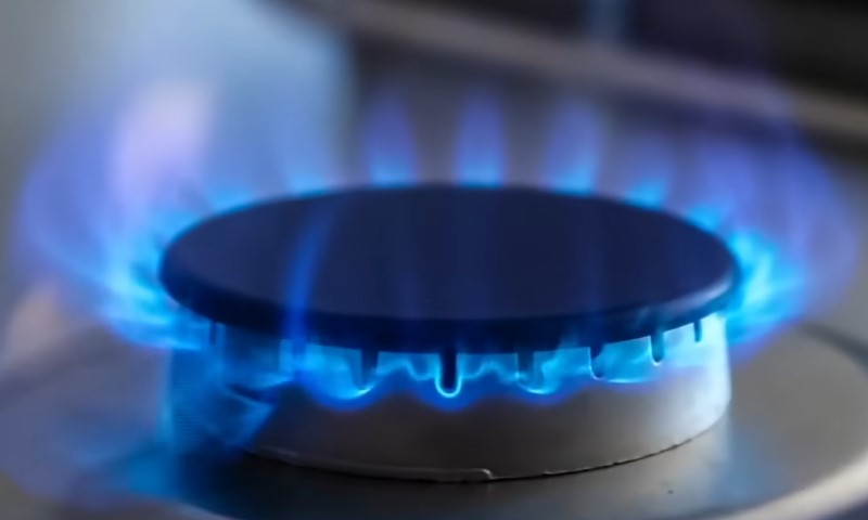 A gas stove with vibrant blue flames burning brightly on the burners