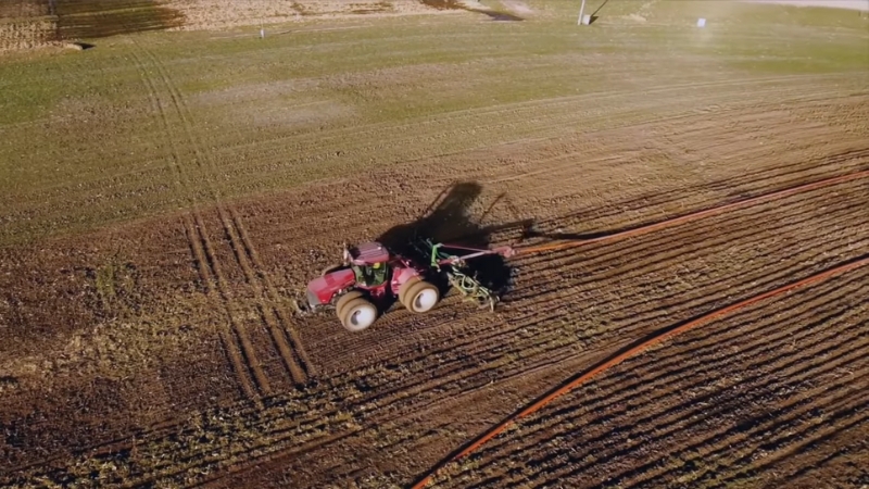 Tractor spreads manure or compost across a field as a natural fertilizer option