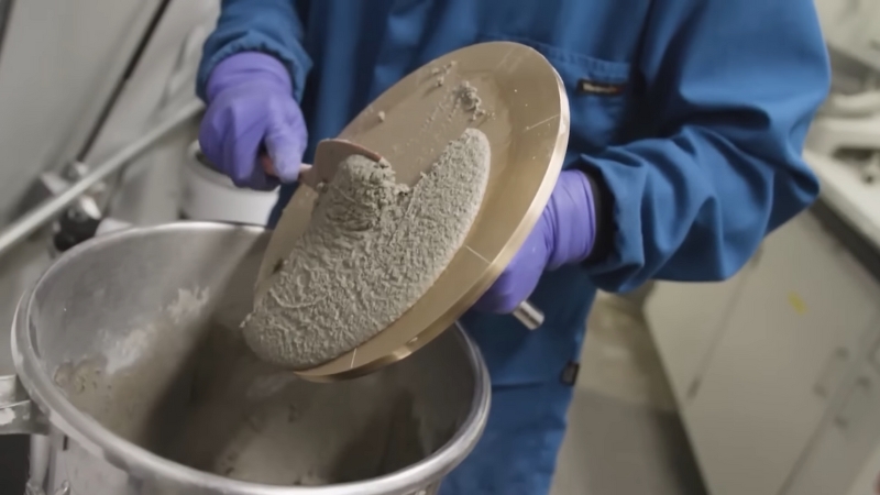 Worker handling low carbon cement mix in a lab for embodied carbon reduction testing