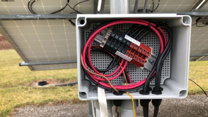 Open junction box on a solar panel showing electrical wiring and connection terminals