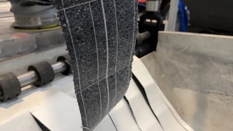 Close-up of shredded photovoltaic module pieces on industrial equipment during solar panel recycling process