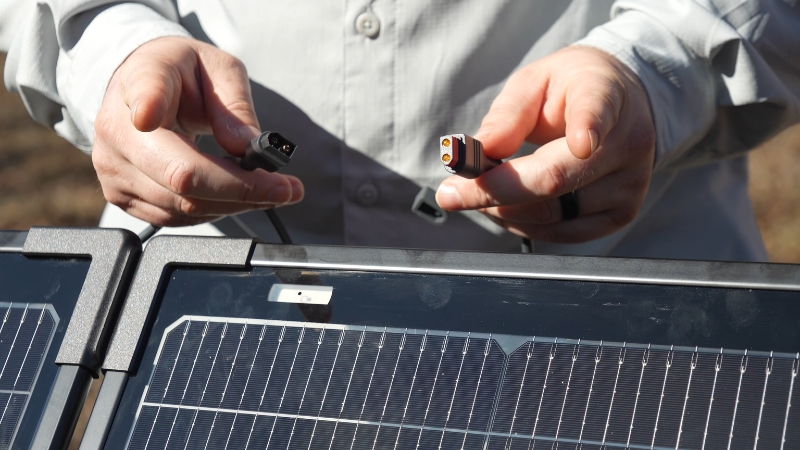 Person connecting cables to a solar panel during battery system setup
