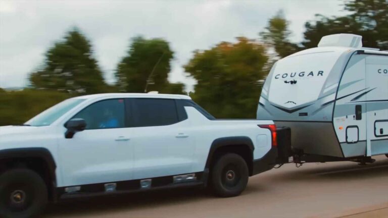 Electric pickup truck towing a travel trailer on a highway