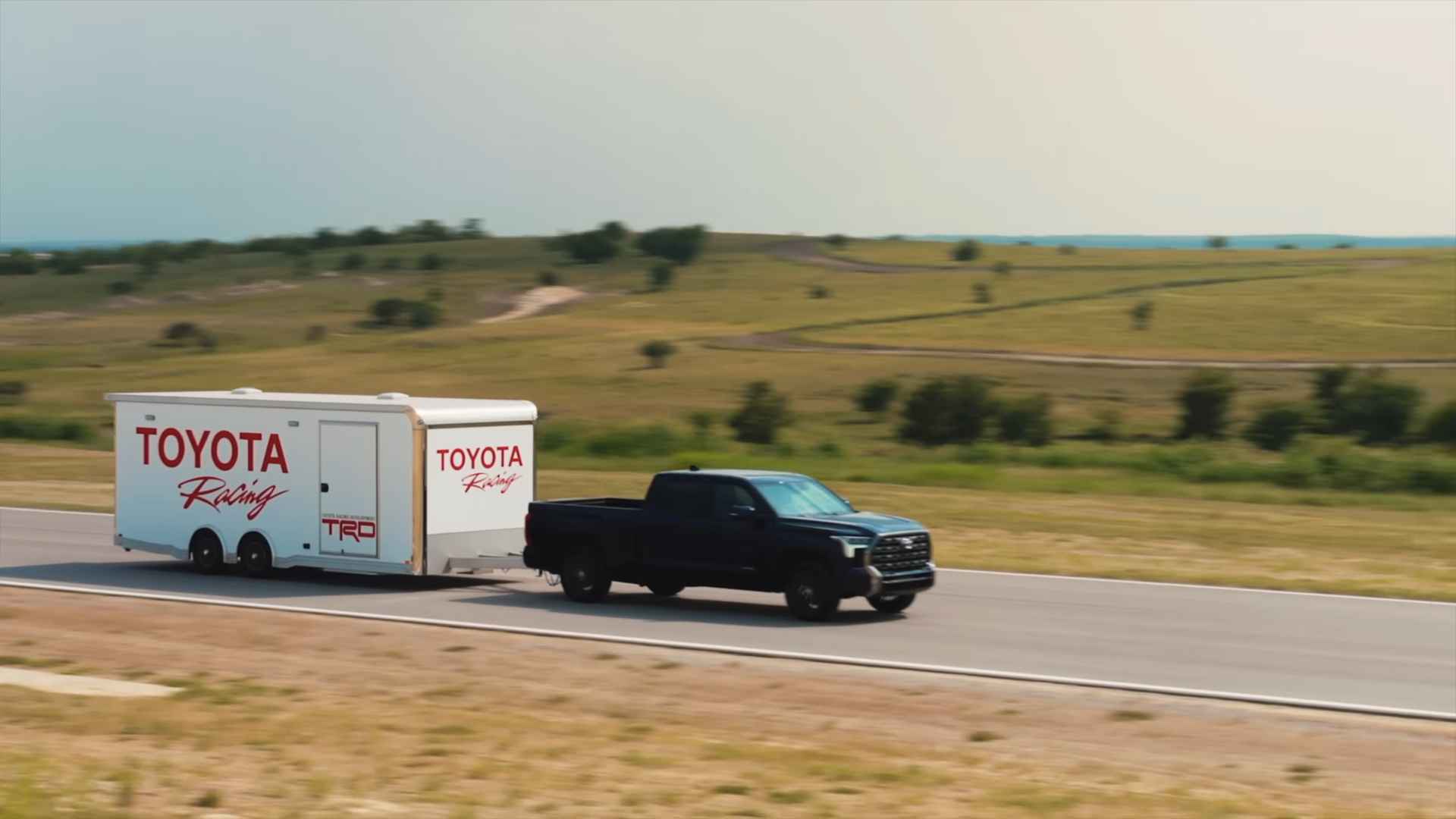 Pickup truck towing a large trailer along an open highway