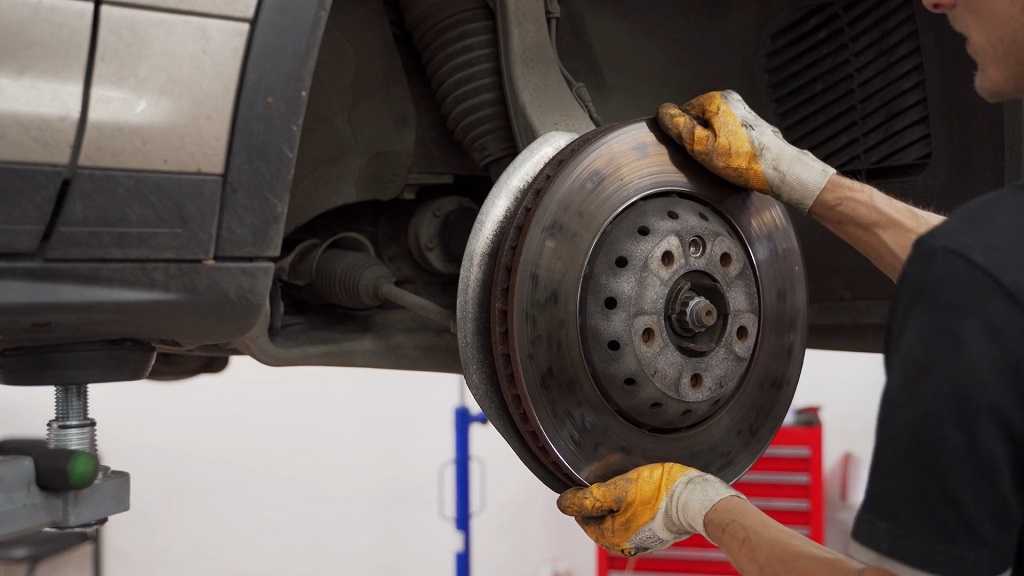 Mechanic installing a brake rotor on a raised vehicle