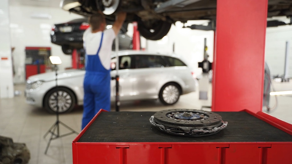 Clutch assembly on workbench with vehicle lifted in repair shop