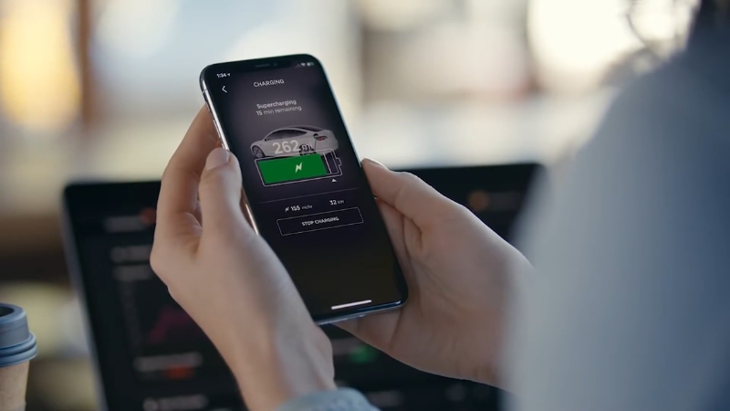 Person checking Tesla charging status on a smartphone app