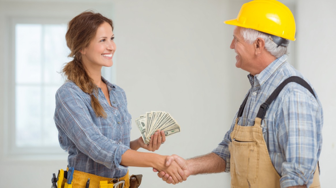 Homeowner shaking hands with a contractor while holding cash, representing heating system installation costs