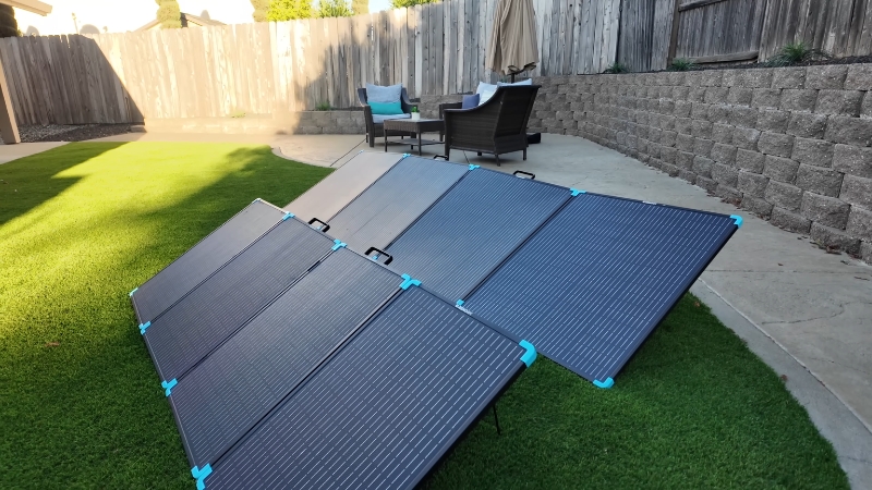 Four 400W solar panels set up on a lawn in a backyard to capture sunlight