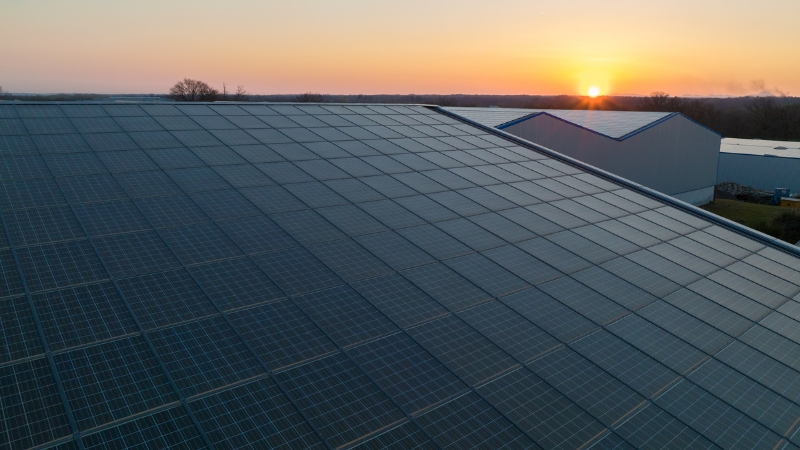 Large rooftop covered with 500W solar panels at sunset on a commercial building
