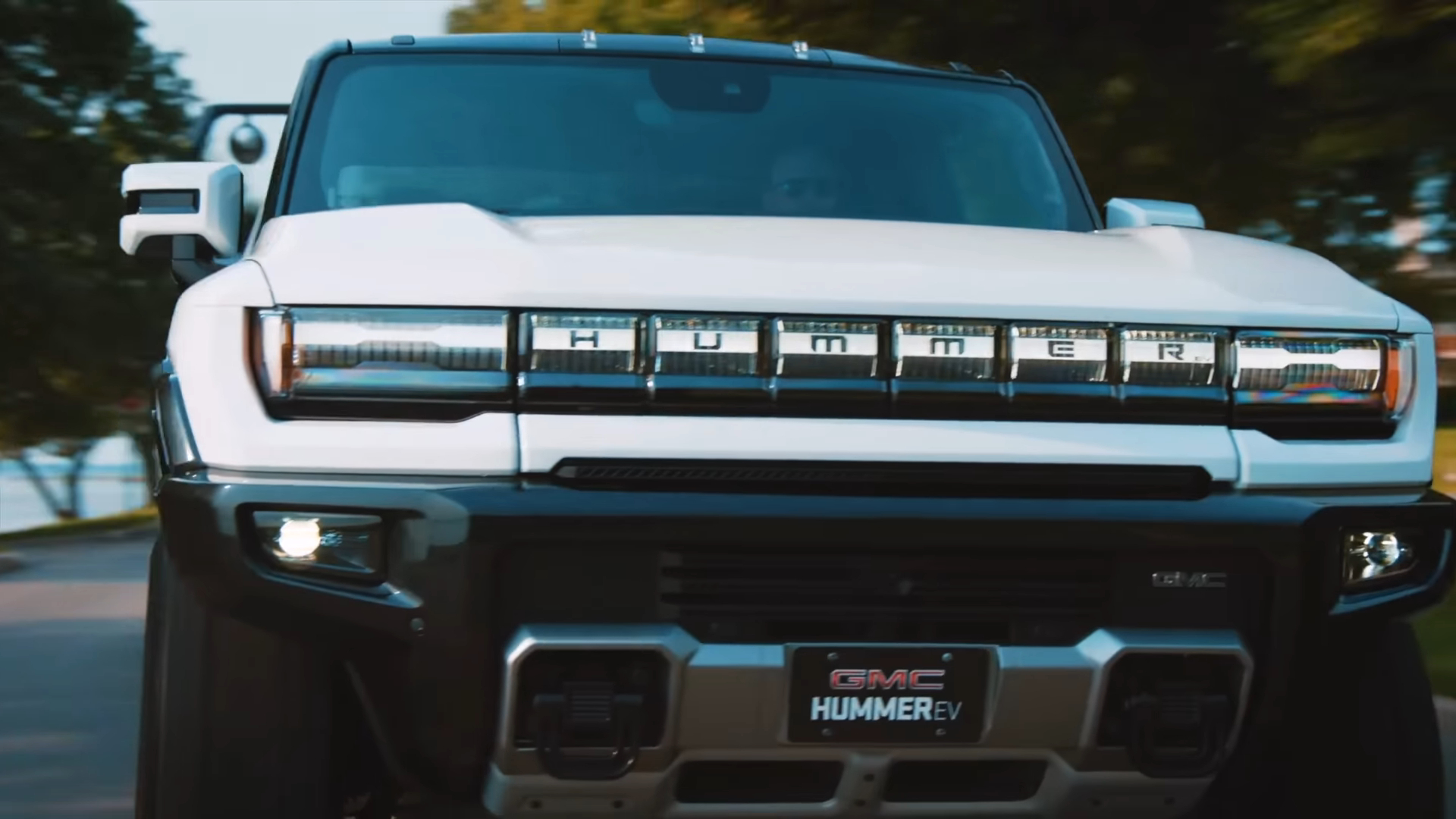 Front view of a large electric pickup truck driving on a road