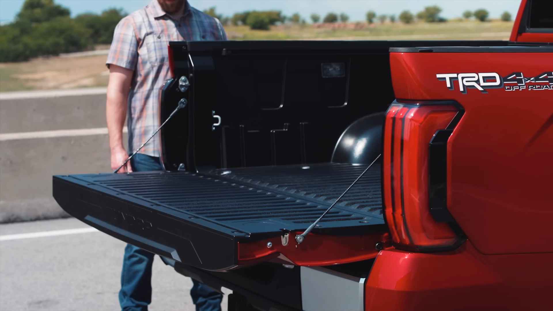 Pickup truck with its tailgate open while a person stands behind it near a roadside
