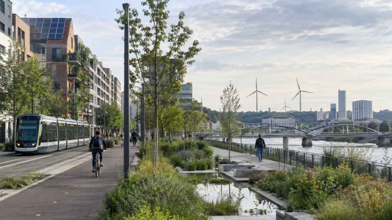 Sustainable European city with tram, bike lane, solar panels and wind turbines.
